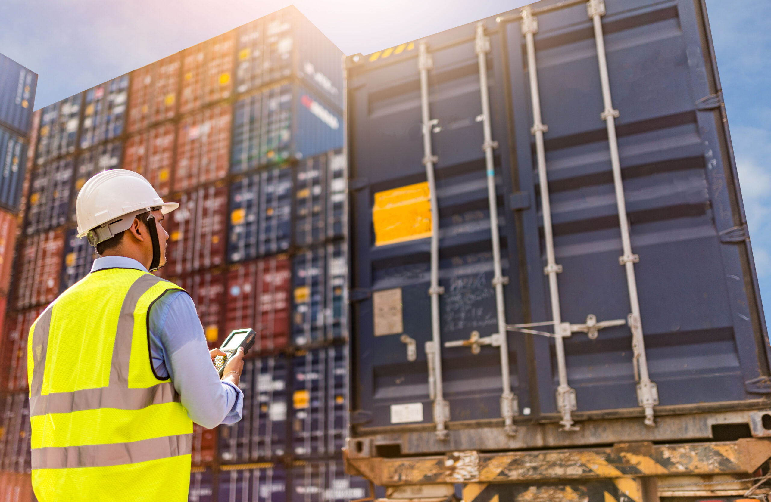 Man with safety vest and helmet looking at containers